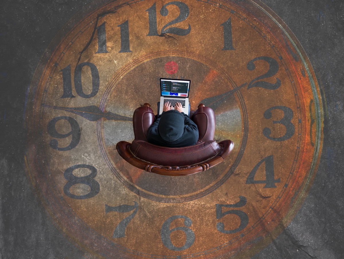 Clock with person sitting in the middle in an armchair on laptop